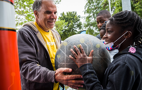 STEM volunteer letting a STEM student hold a piece of orbital debris