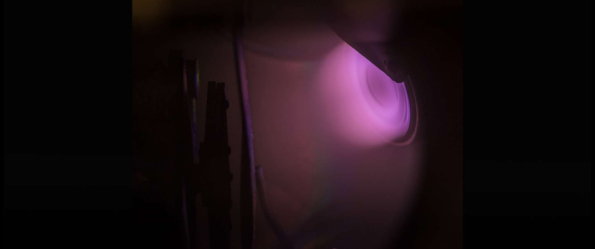 Beam Me Up!: Plasma plume in a physical vapor deposition (PVD) magnetron sputtering chamber. This chamber is used to create optical coatings and thin films, which are essential for sensor systems, thermal control strategies and photovoltaic power sources.