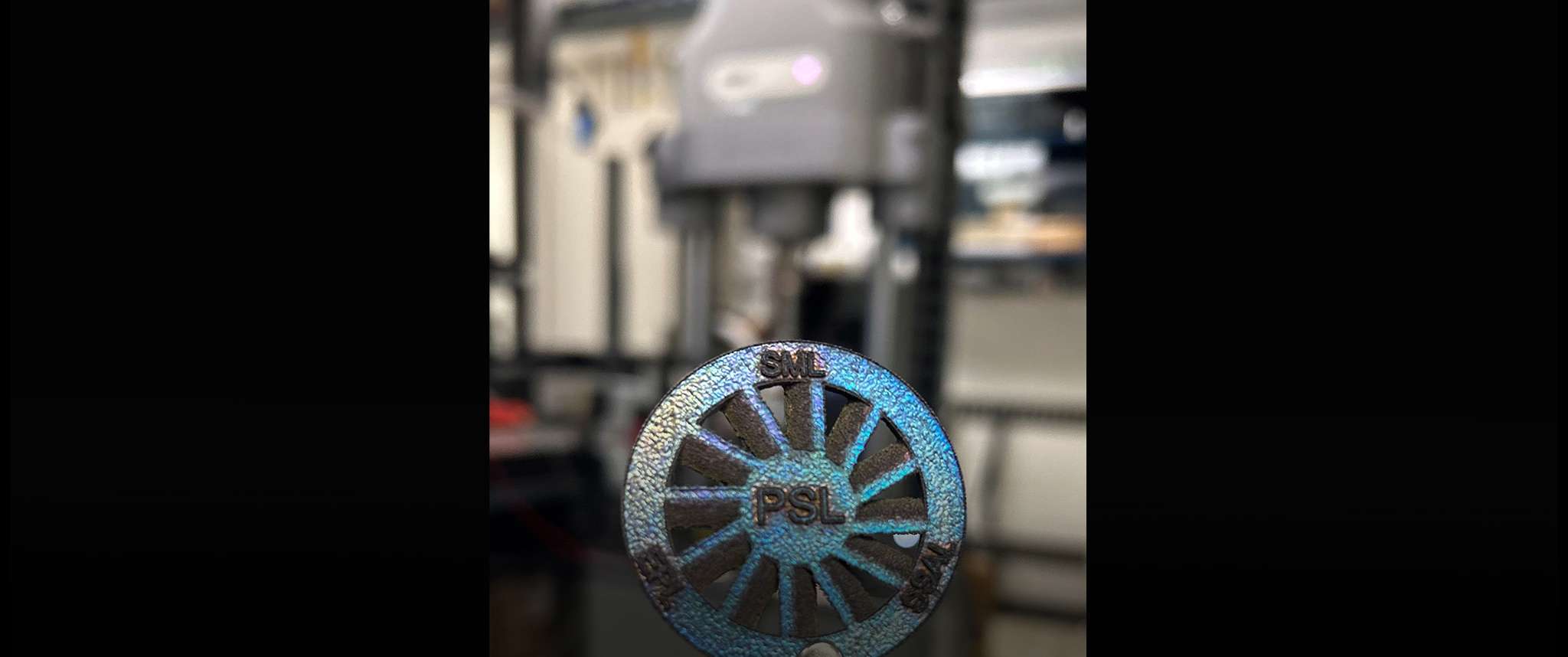 Focus on the Prize: Artsy portrait focus style picture of 3D printed sample with 1 micron thick thin film coating in front of lab tools such as in instron.