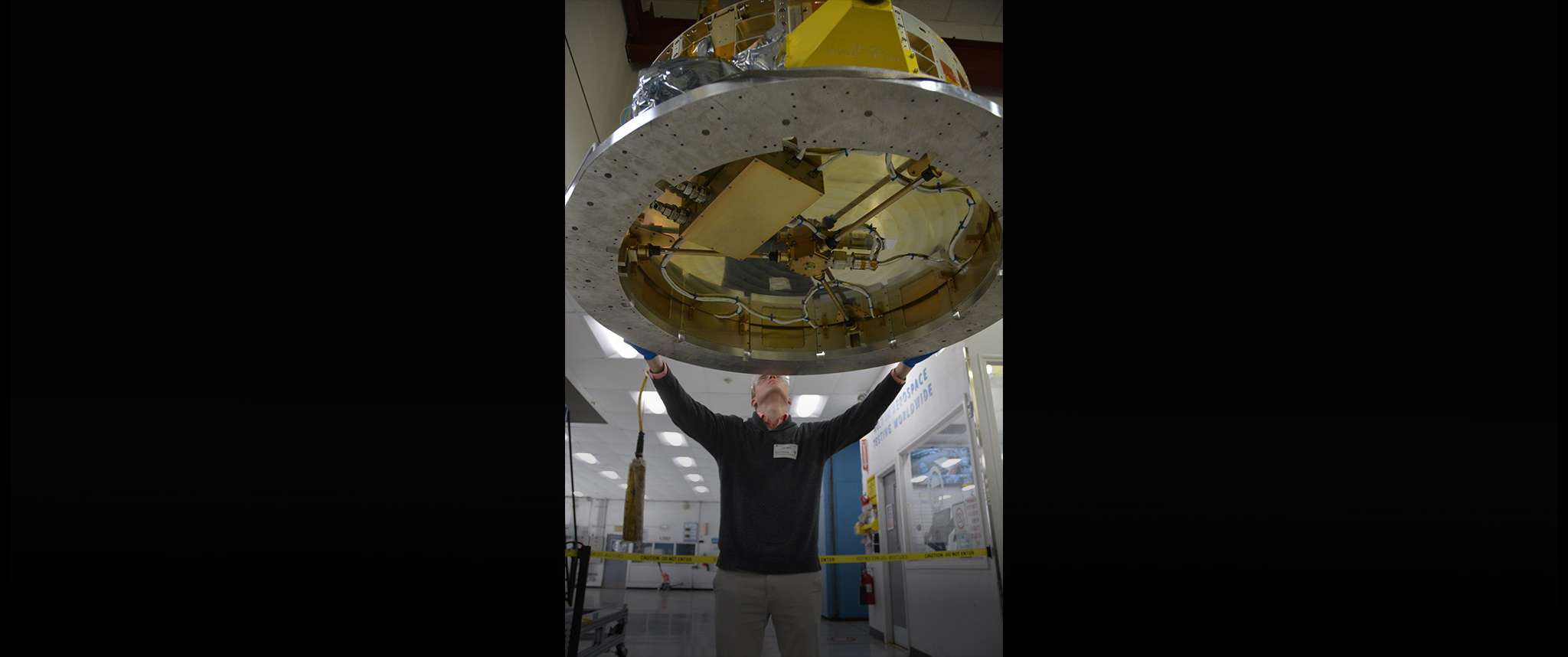 Superhuman Strength: Brian is “lifting” the Dispenser for the DiskSat program. The Dispenser launches four DiskSats. A DiskSat is a new flat circular satellite that has all the capabilities of standard AeroCubes but in a new form factor that provides greater surface area for solar cells and payloads.