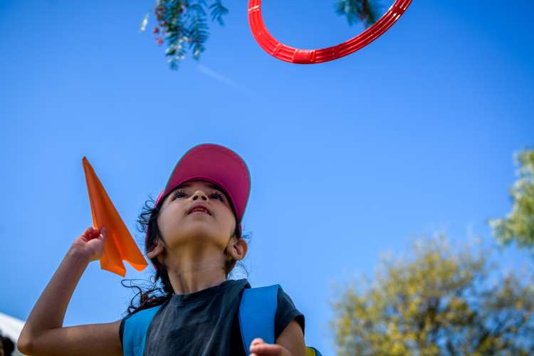 Child throwing a paper airplane.