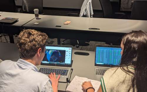 A man and woman typing on laptops.